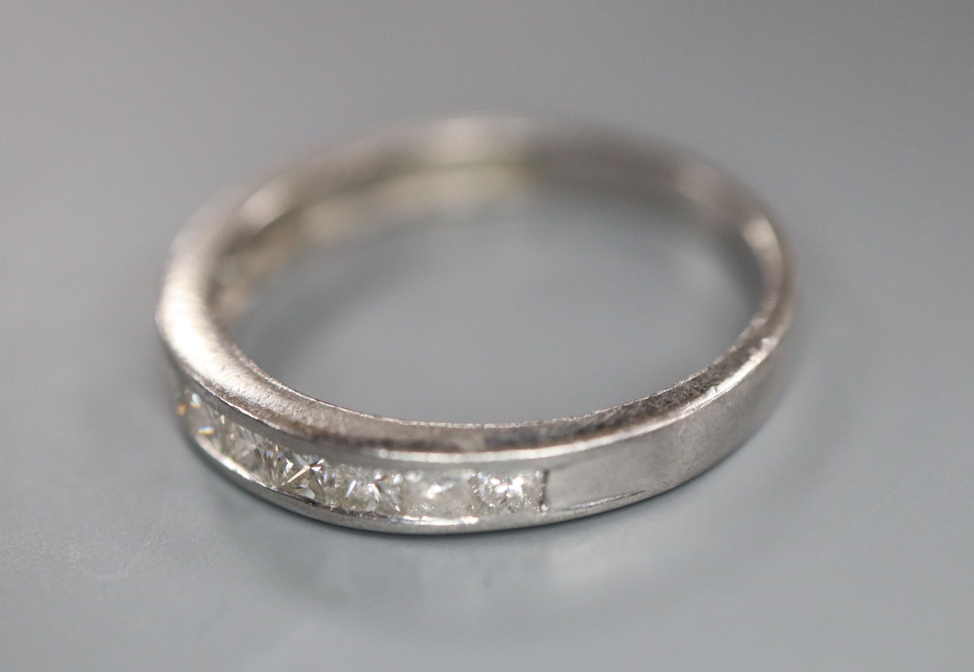 A modern platinum and channel set ten stone diamond half eternity ring, size N, gross 2.9 grams,